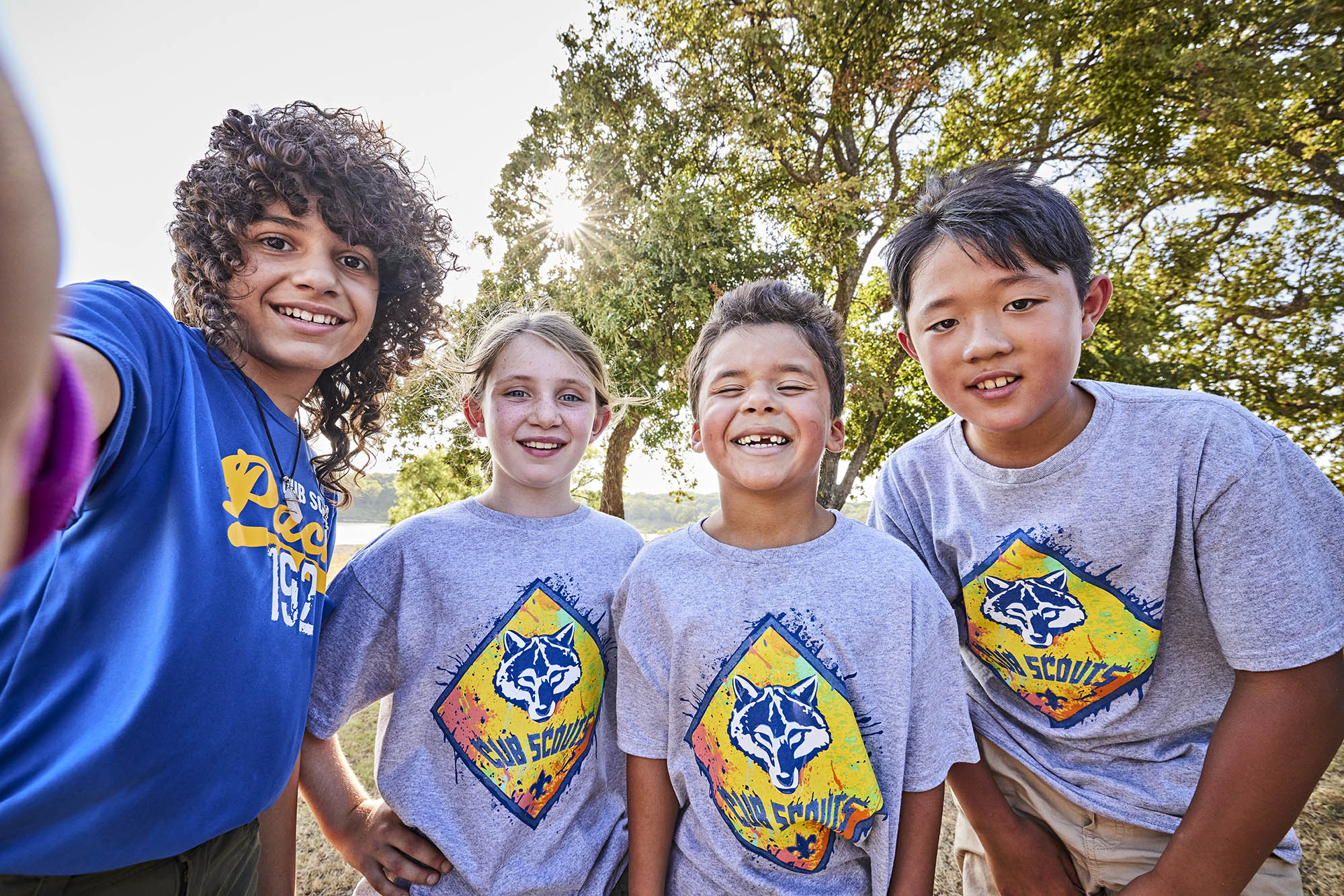 group of four Cub Scouts hugging and smiling